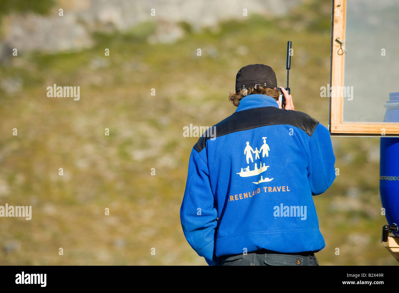 Un tour della Groenlandia guida utilizzando un telefono satellitare in una zona remota a Camp Victor su Greenlands west coast Foto Stock