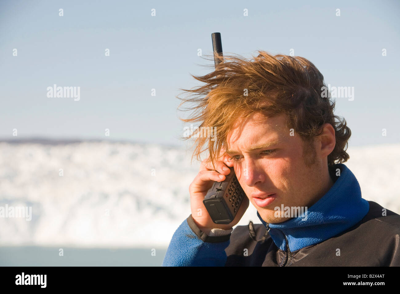 Un tour della Groenlandia guida utilizzando un telefono satellitare in una zona remota a Camp Victor su Greenlands west coast Foto Stock