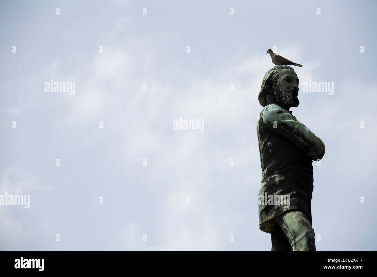 Un uccello si appoggia sulla testa di una statua presso la necropoli Cristobal Colon nel cimitero di Havana, Cuba Foto Stock