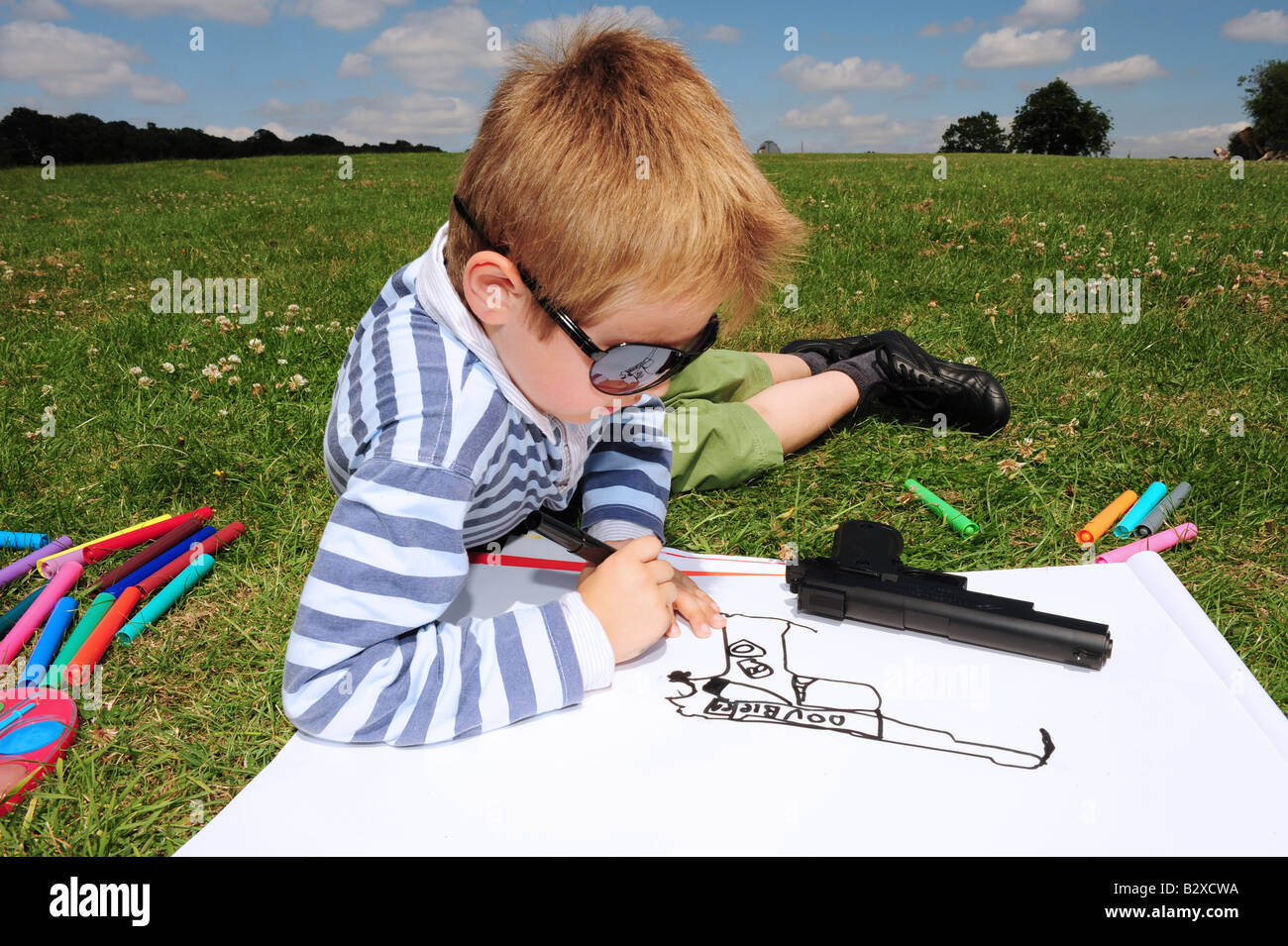 L'immagine orizzontale di un piccolo ragazzo il disegno di una foto della sua pistola giocattolo nel parco su una giornata d'estate in Kent England Foto Stock