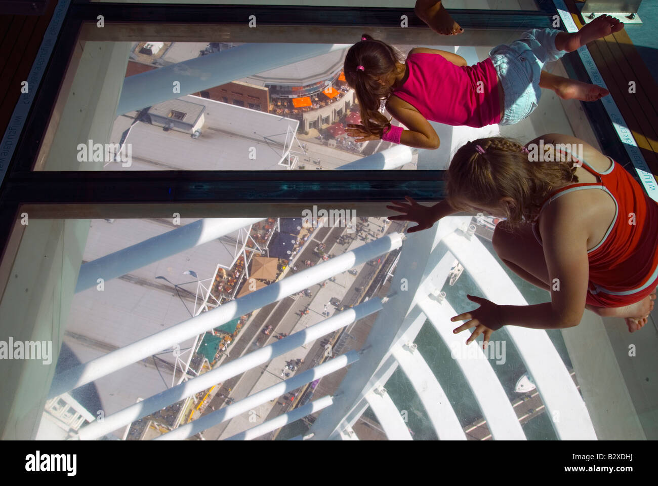 Due bambini guardano a terra 100m al di sotto di esse attraverso il pavimento di vetro della Spinnaker Tower. Foto Stock