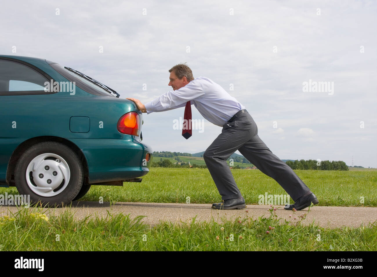 Imprenditore spingendo un auto con serbatoio del combustibile vuoto Foto Stock