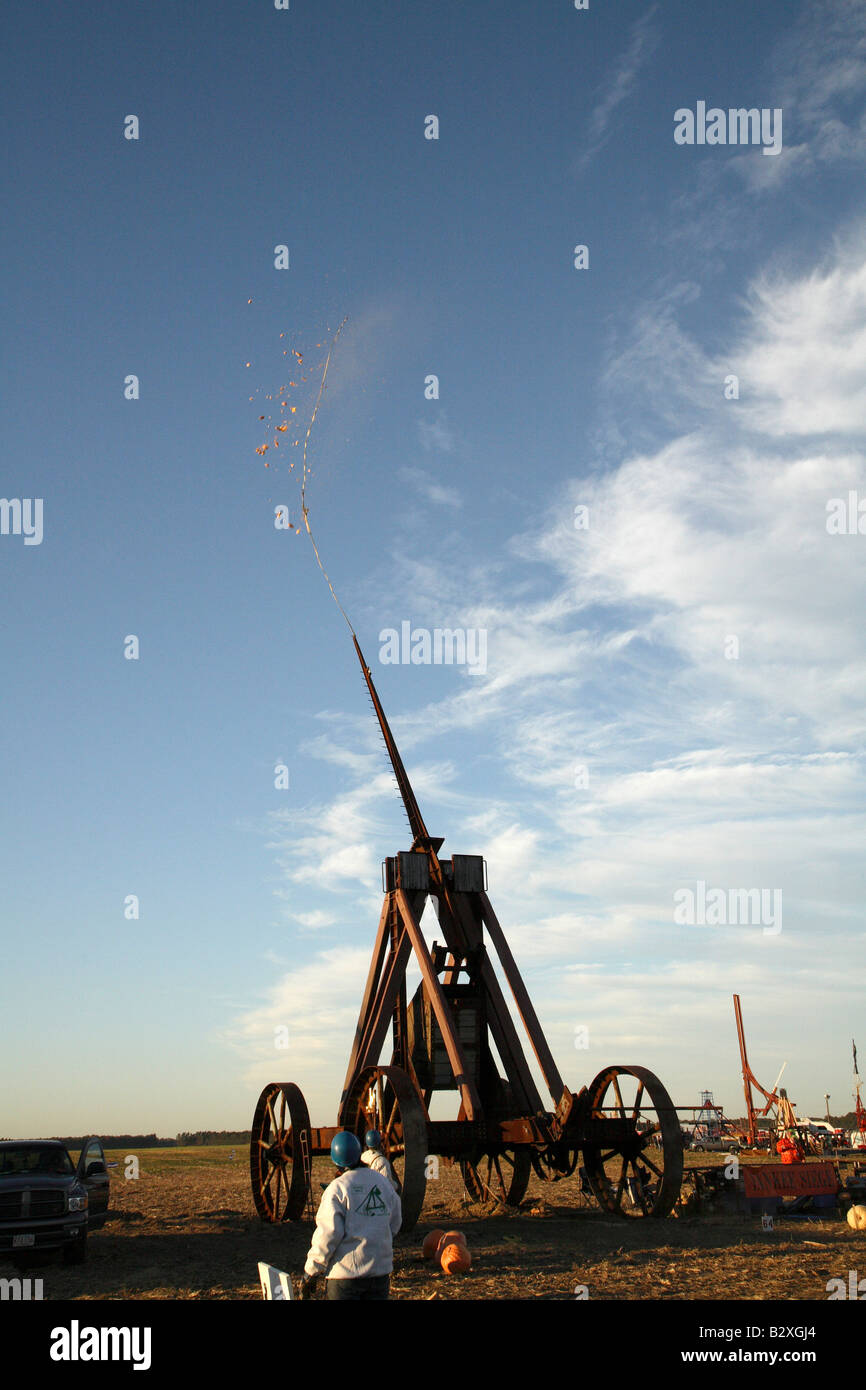 Enormi ruote di ferro Yankee assedio Trebuchet con FLING FESTIVAL braccio rivolto in avanti come la zucca vola fuori sopra il campo in pezzi. Foto Stock
