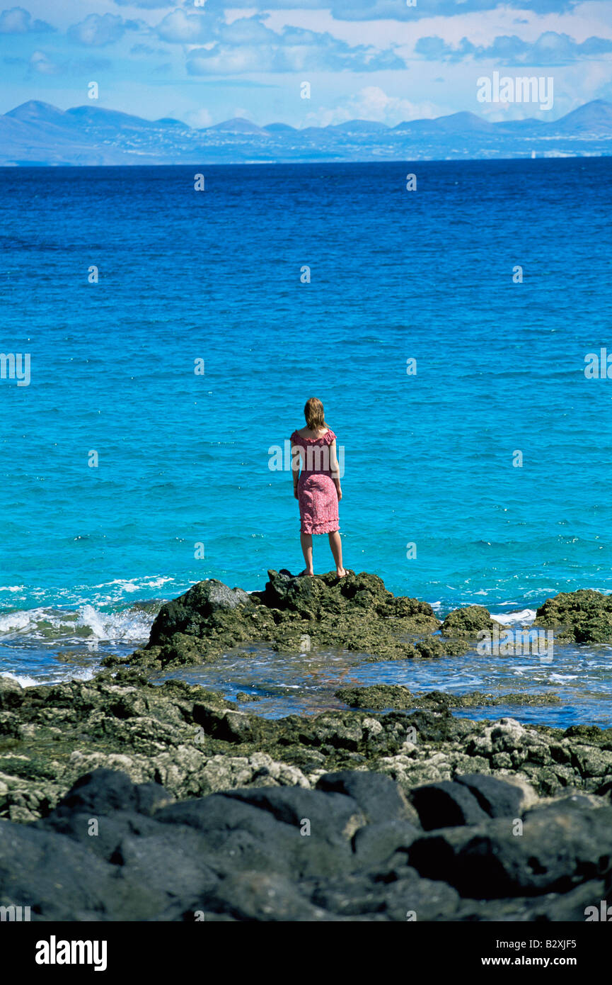 Donna all'aperto in piedi su grandi rocce Oceanside Foto Stock
