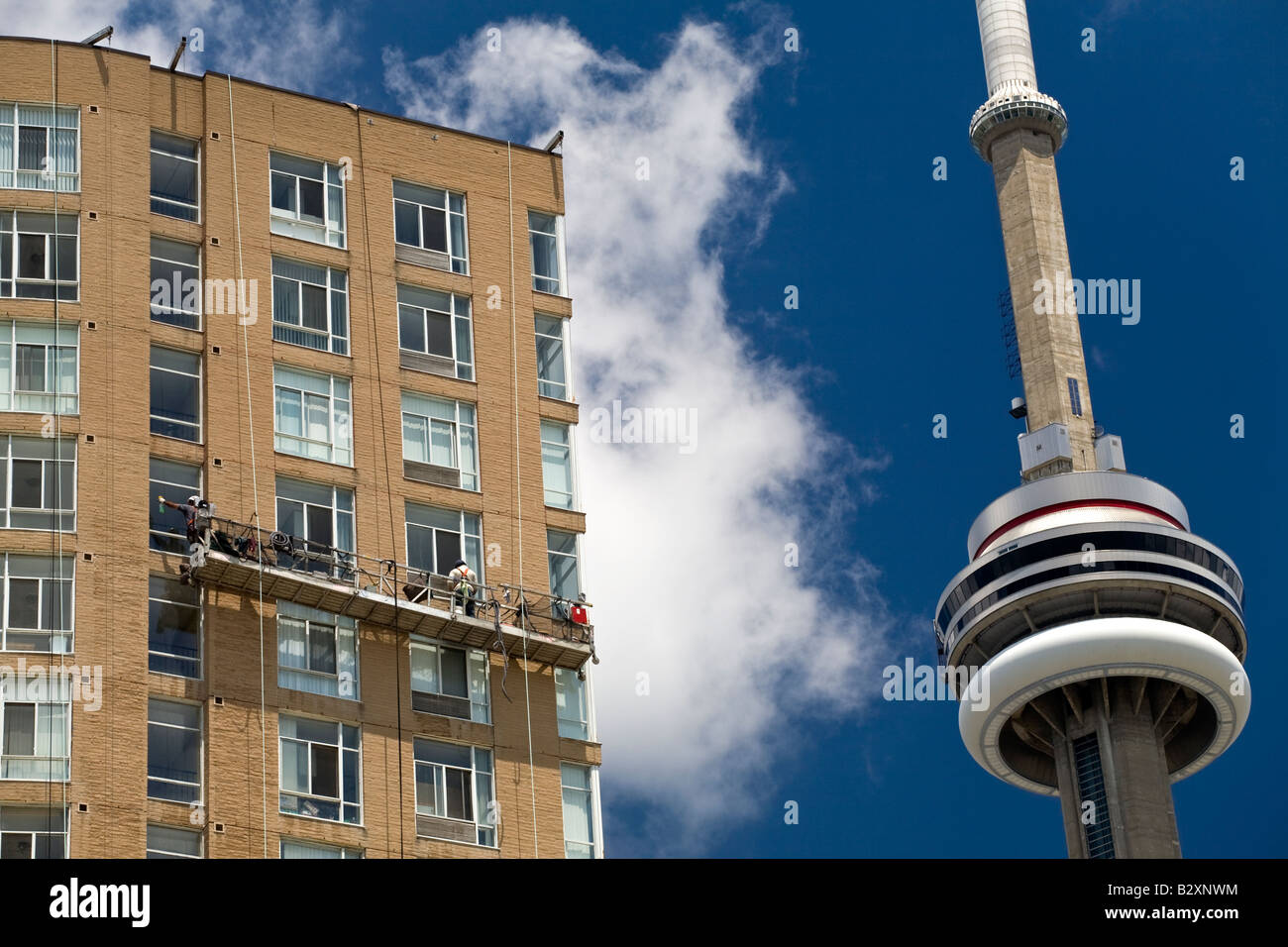 Due detergenti per finestre lavorando su un alto accanto alla CN Tower a Toronto, Ontario, Canada. Foto Stock
