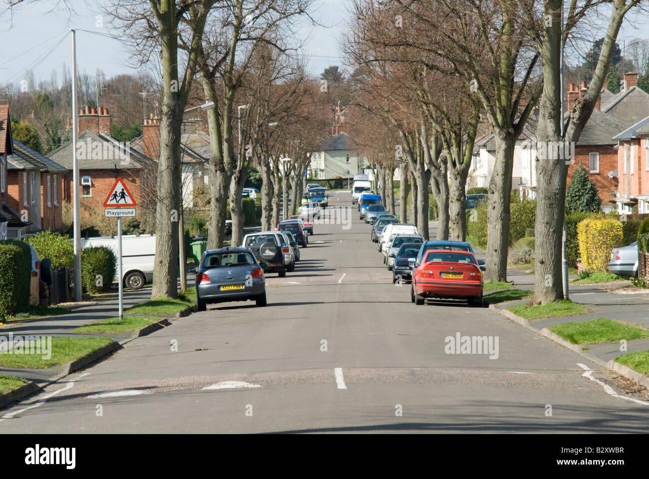 Auto parcheggiate in una strada suburbana con cunette di velocità per rallentare il traffico nel Regno Unito. Foto Stock