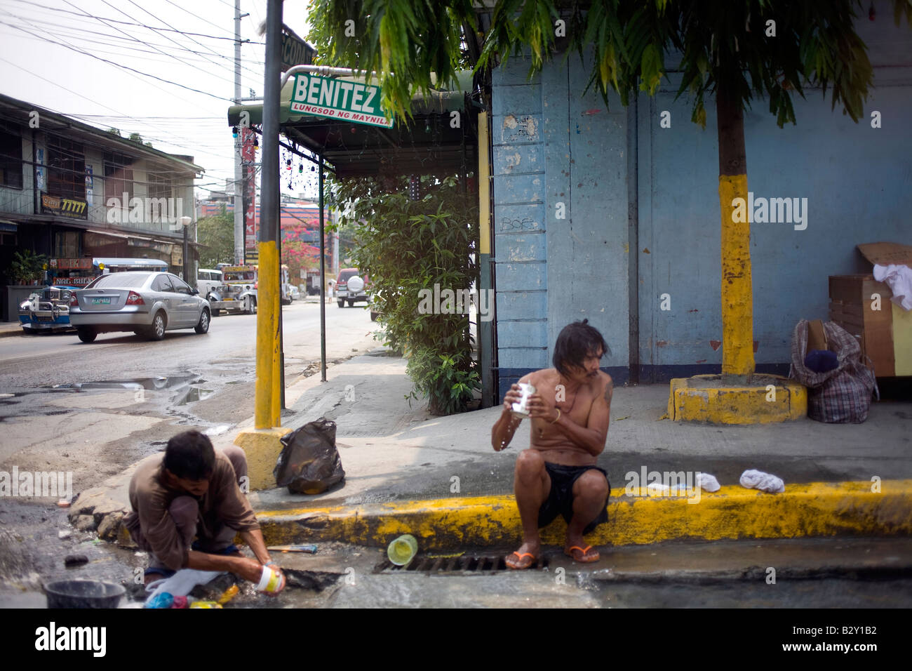 Due poveri filippini laverà con acqua in una gronda a Manila nelle Filippine. Foto Stock
