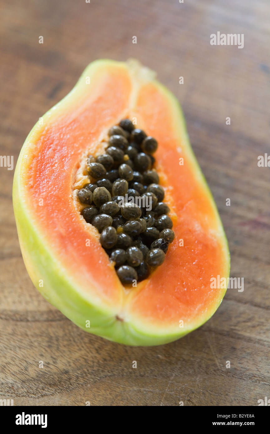 Tagliate a metà la papaya sulla superficie di legno Foto Stock