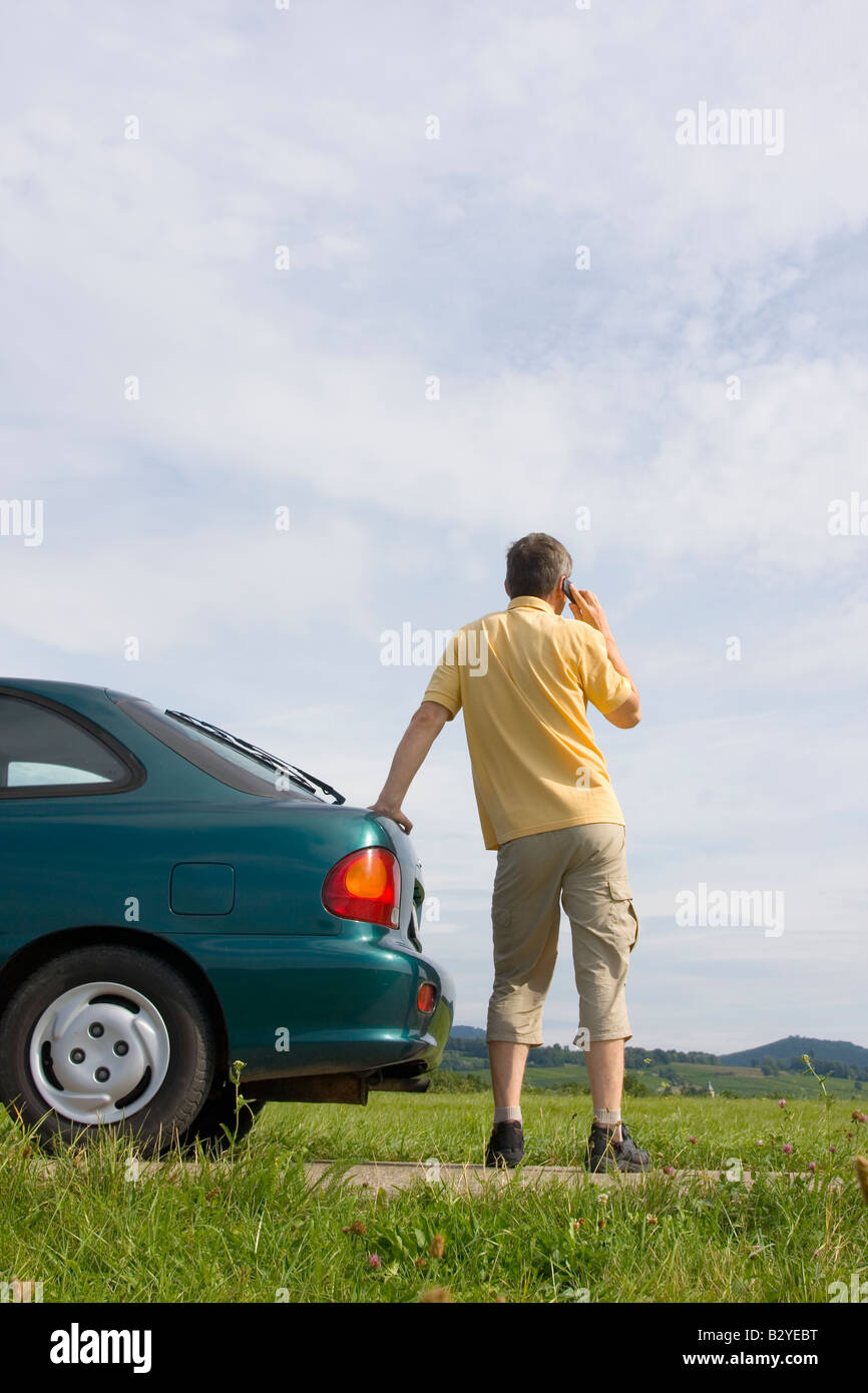 L'uomo parlando al cellulare accanto alla sua vettura che ha un guasto o di un serbatoio del combustibile vuoto Foto Stock