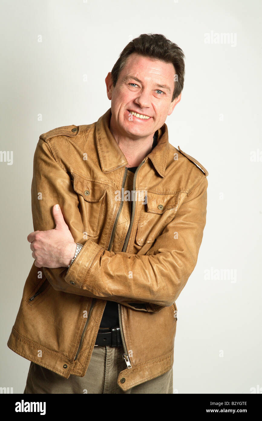 L uomo nella sua 40s sorridente indossa una giacca di pelle - braccia incrociate Foto Stock