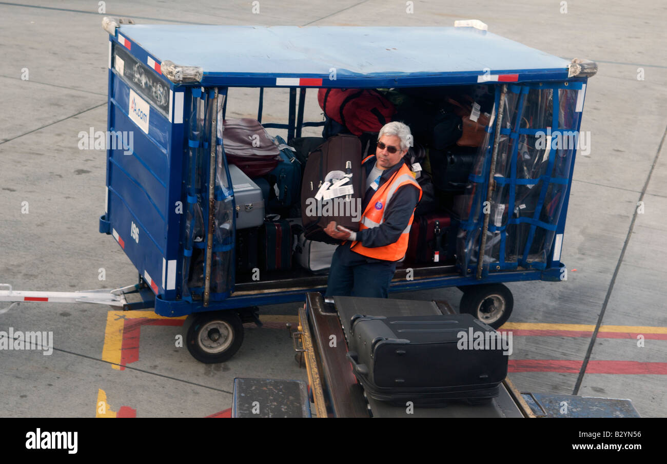 Un bagaglio carichi di gestore di una valigia su di un nastro trasportatore a Dallas Fort Worth International Airport in Texas, Stati Uniti Foto Stock