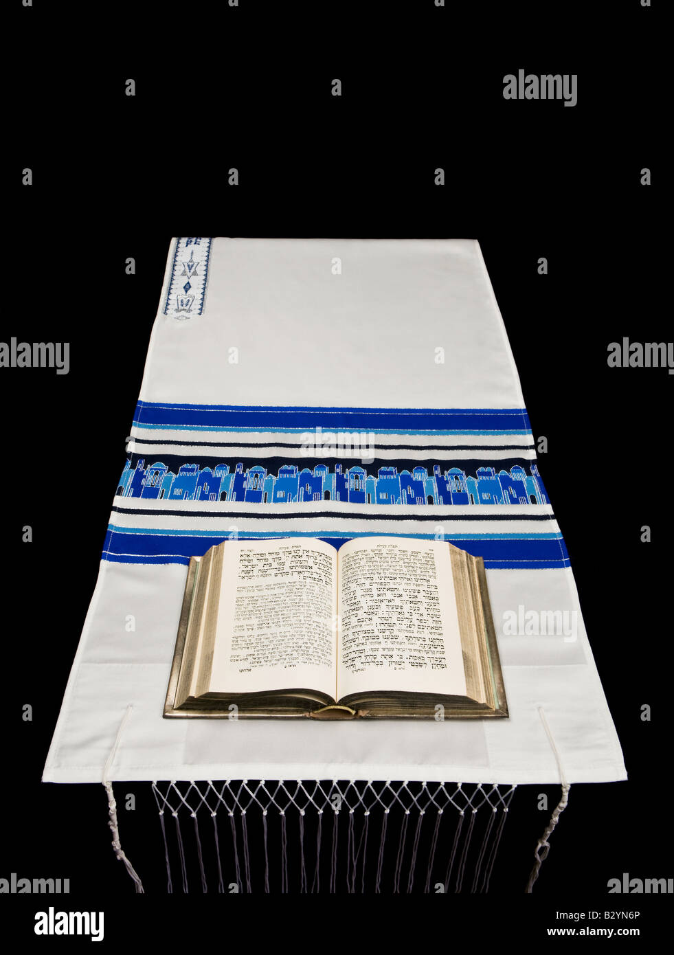 Una preghiera ebraica libro o Siddur, su uno scialle rituale o tallit, contro uno sfondo nero. Foto Stock