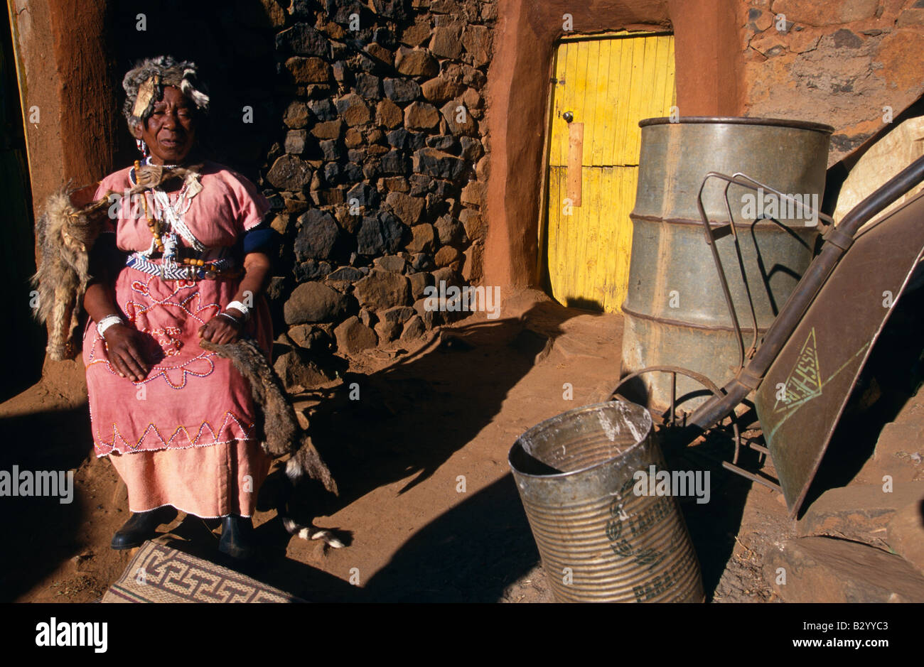 Sangoma, (tradizionale africana di guaritore) seduto fuori casa indossando il costume tradizionale, ritratto, Lesotho, Africa Foto Stock