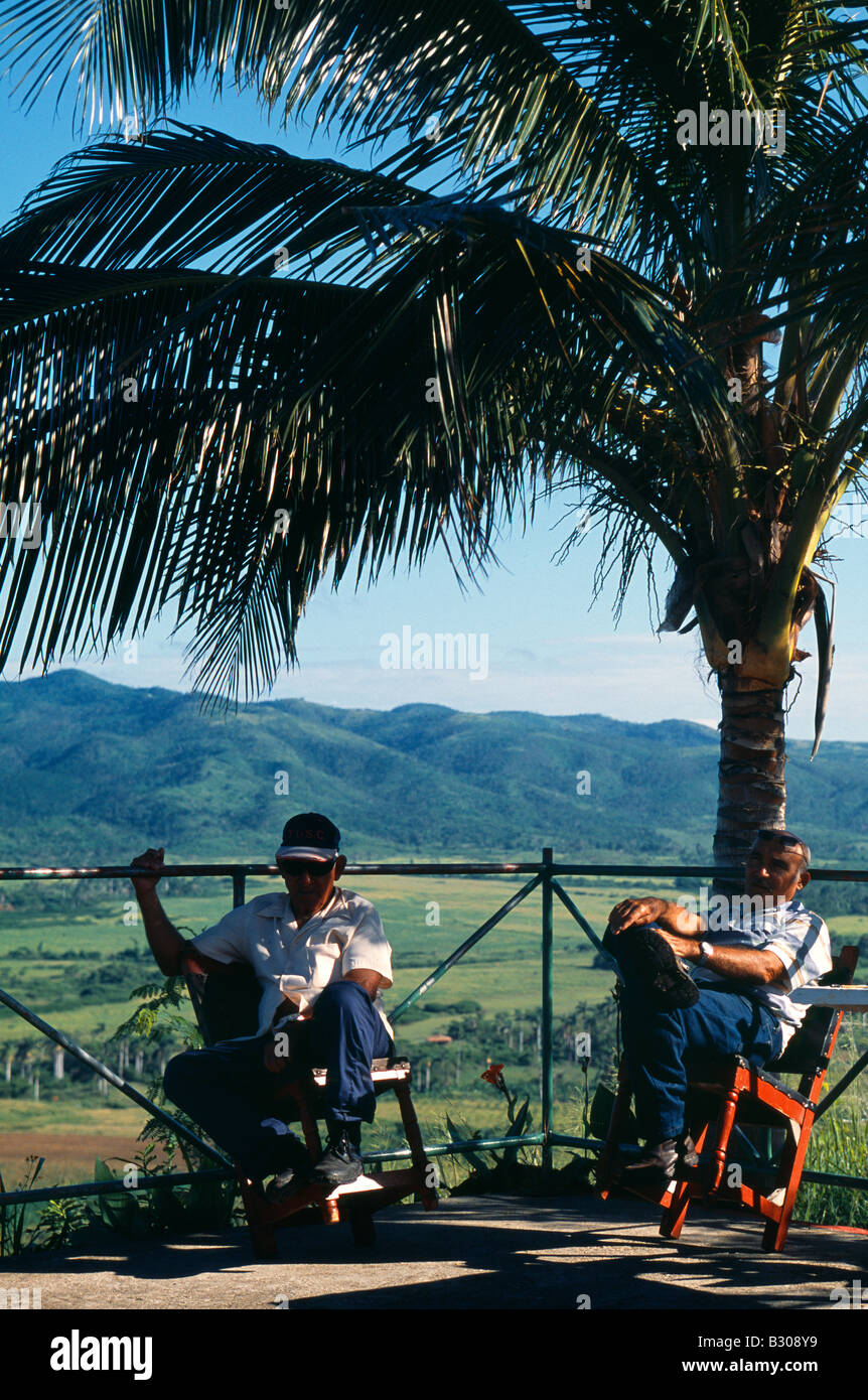 Gli uomini cubani rilassarsi all'ombra di una palma che si affaccia alle piantagioni che circonda la città patrimonio mondiale di Trinidad, Cuba Foto Stock