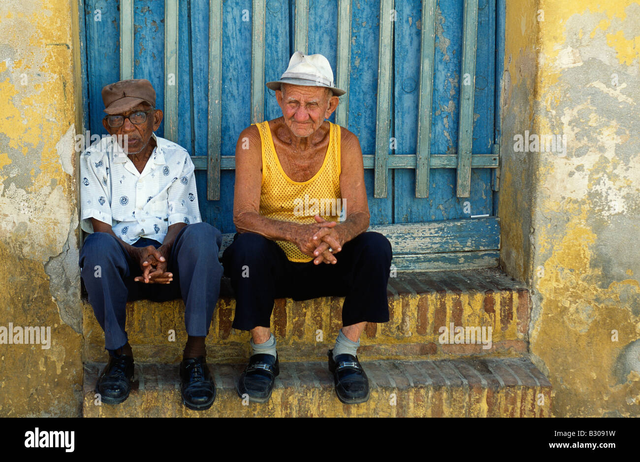 Cubani, uomini seduti all'ombra di una porta nella città patrimonio mondiale di Trinidad, Cuba orientale Foto Stock