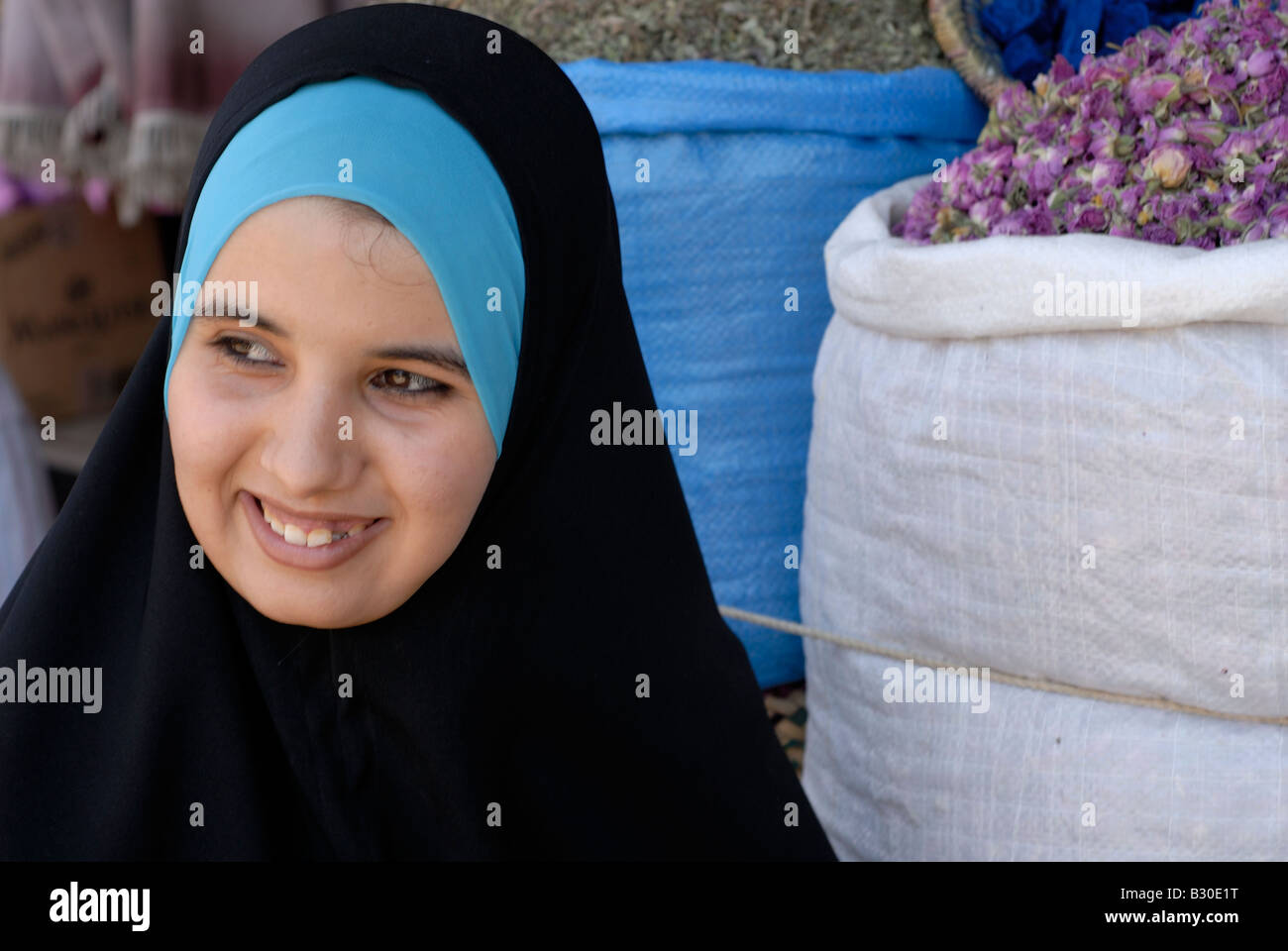 Nord Africa Marocco Marrakech souk delle spezie giovane donna in hijab signora in abito tradizionale le spezie e le rose rosa in vendita sorridente Foto Stock
