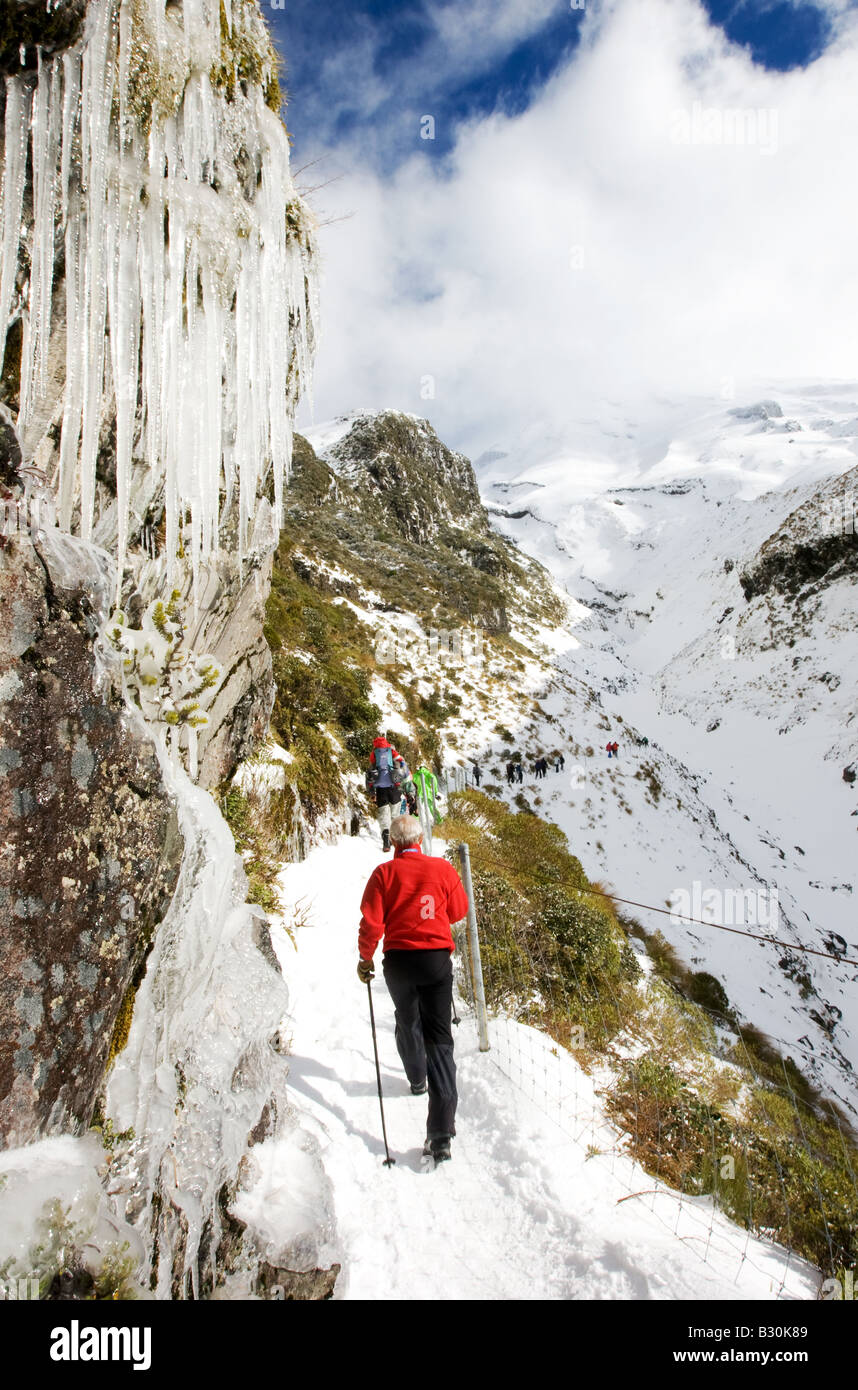 Un uomo camminare sotto ghiaccioli su una pista di montagna. Foto Stock