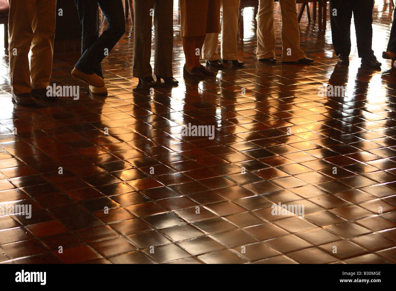 Una linea di gambe come persone in piedi in una linea di riflettere su un pavimento. Foto Stock