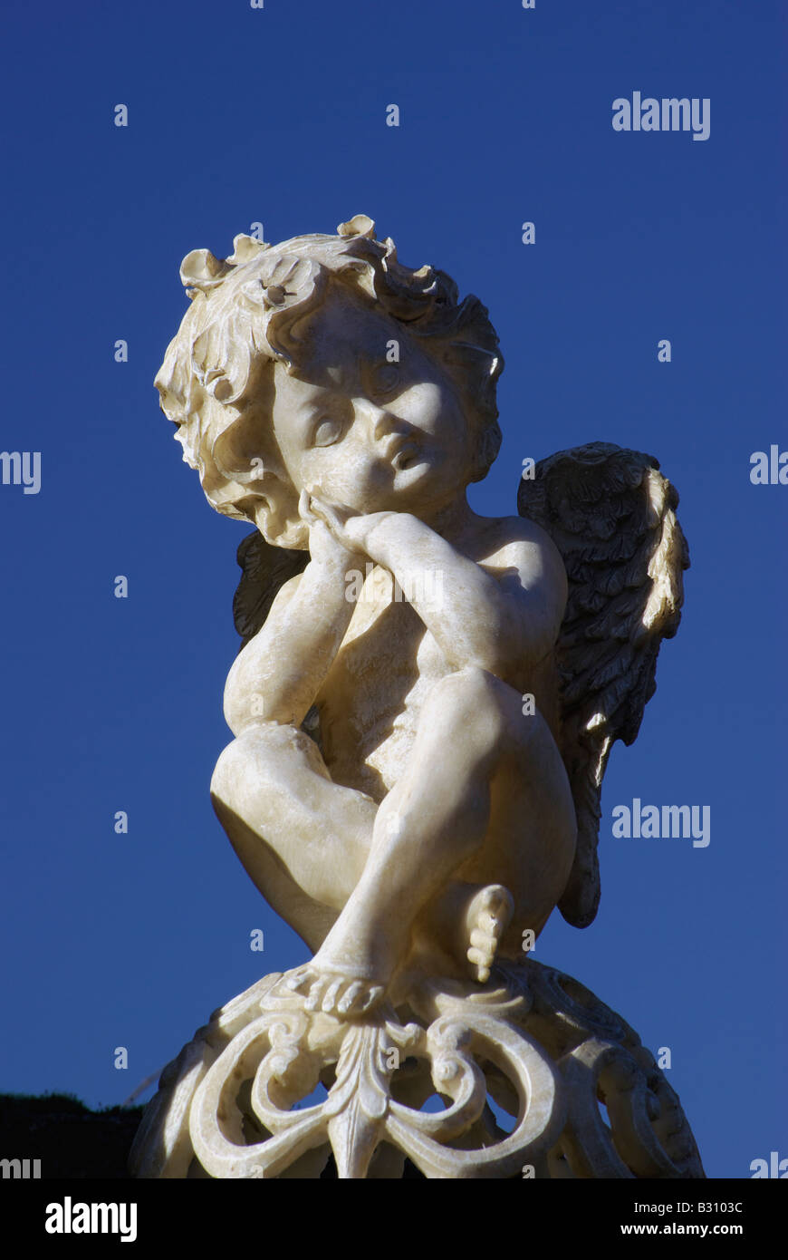 La scultura di un bambino innocente angelo putto su un grave contro un cielo blu Foto Stock