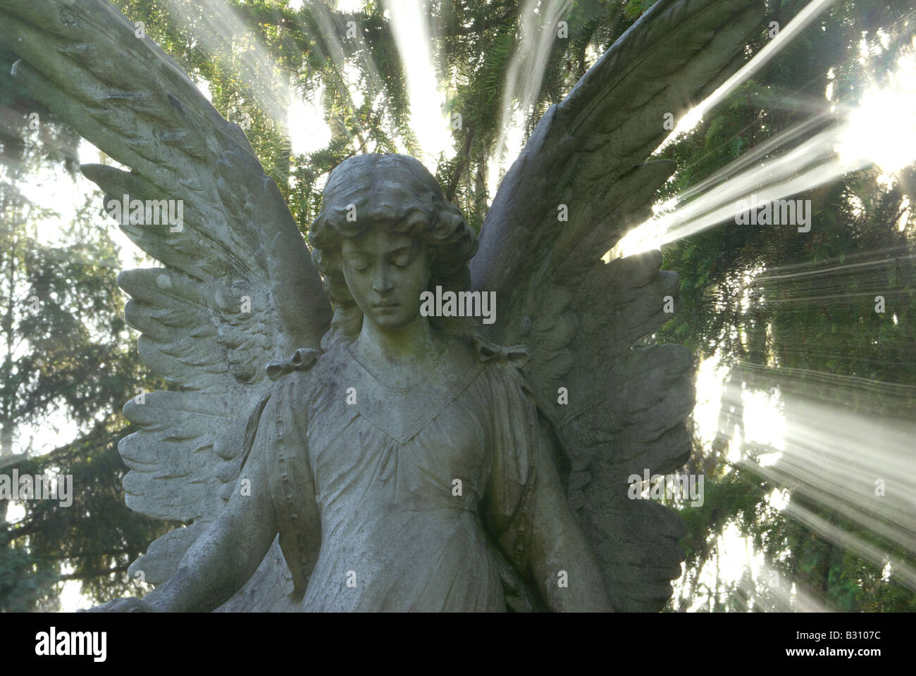 Angelo permanente di scultura circondato da una splendida aura di luce Foto Stock