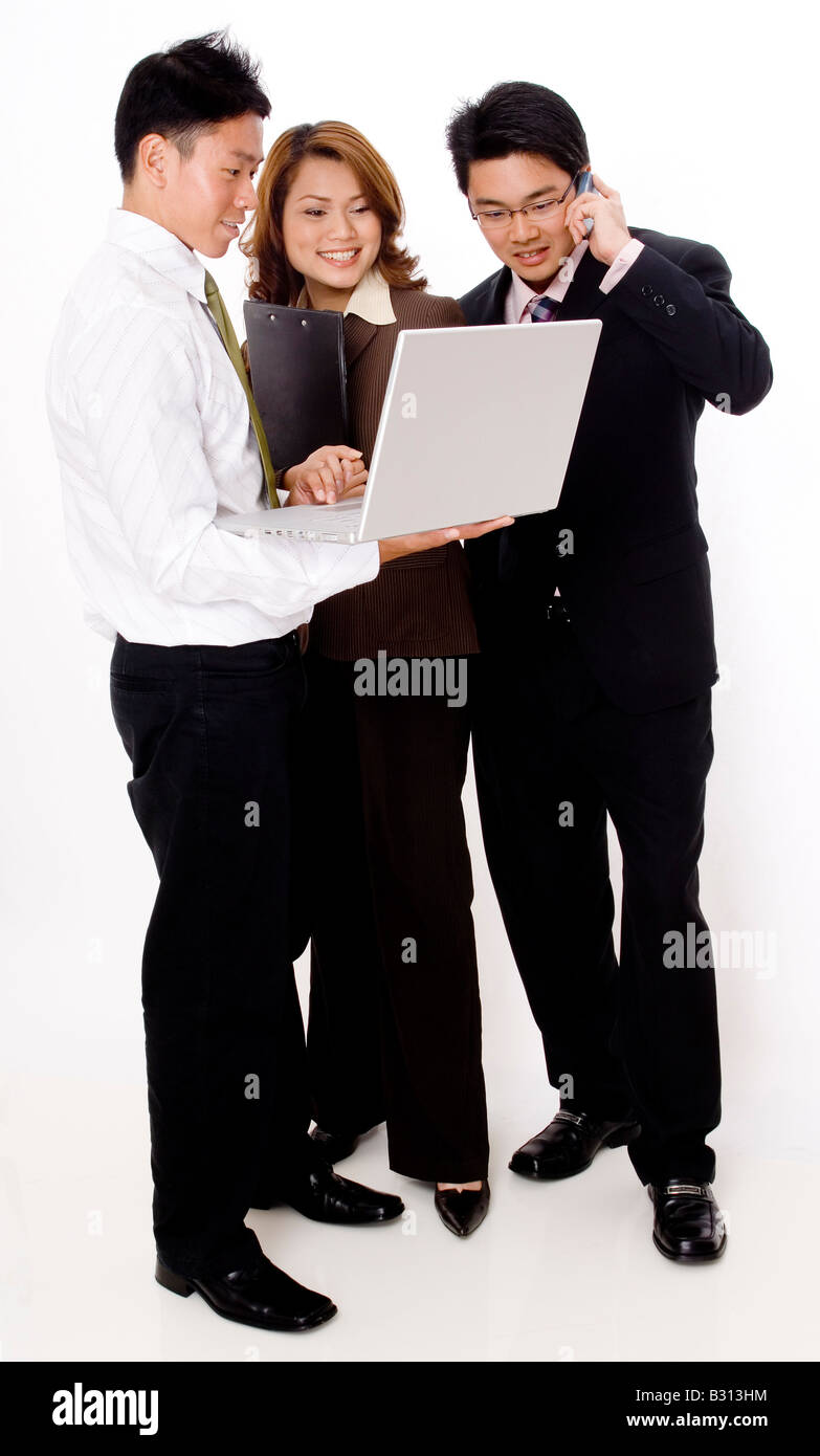 Tre giovani sorridente la gente di affari in cerca di un computer portatile Foto Stock