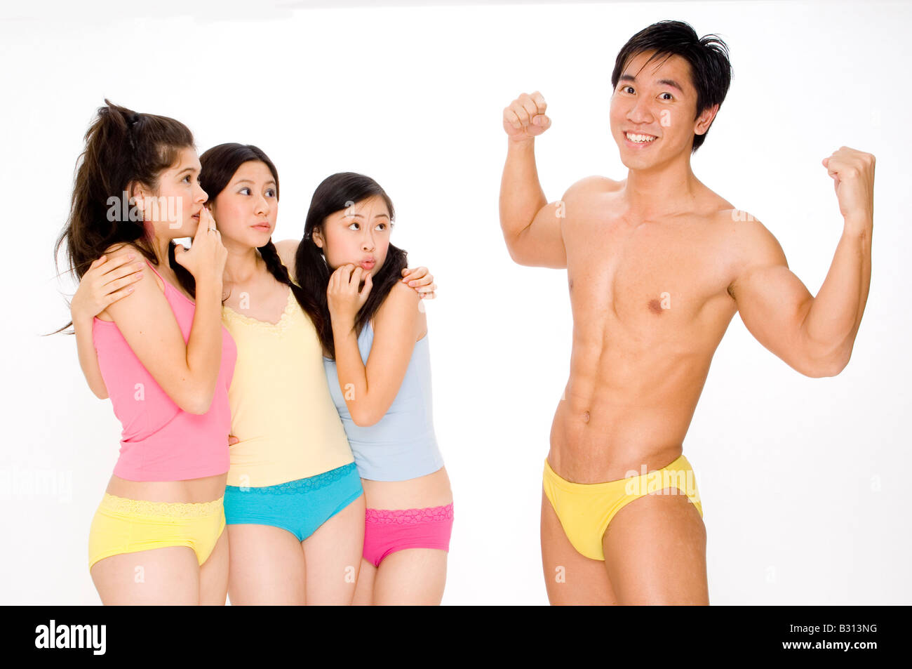 Un muscoloso uomo asiatico si mette in mostra la sua prestanza fisica a tre giovani donne Foto Stock