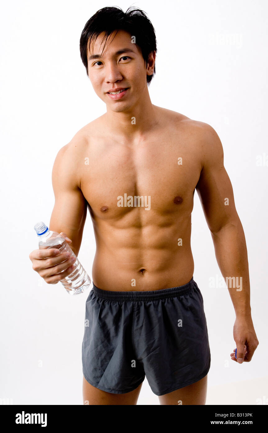 Una ben costruita giovane maschio asiatici tenendo una bottiglia di acqua Foto Stock