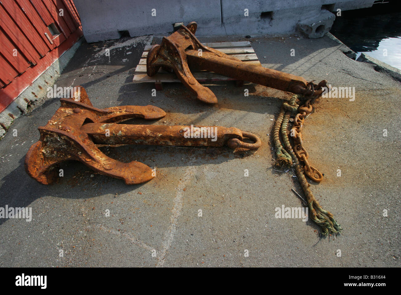 OId arrugginito, coppia di ancore oggetto di pratiche di dumping sul molo di un piccolo porto in Norvegia. Foto Stock