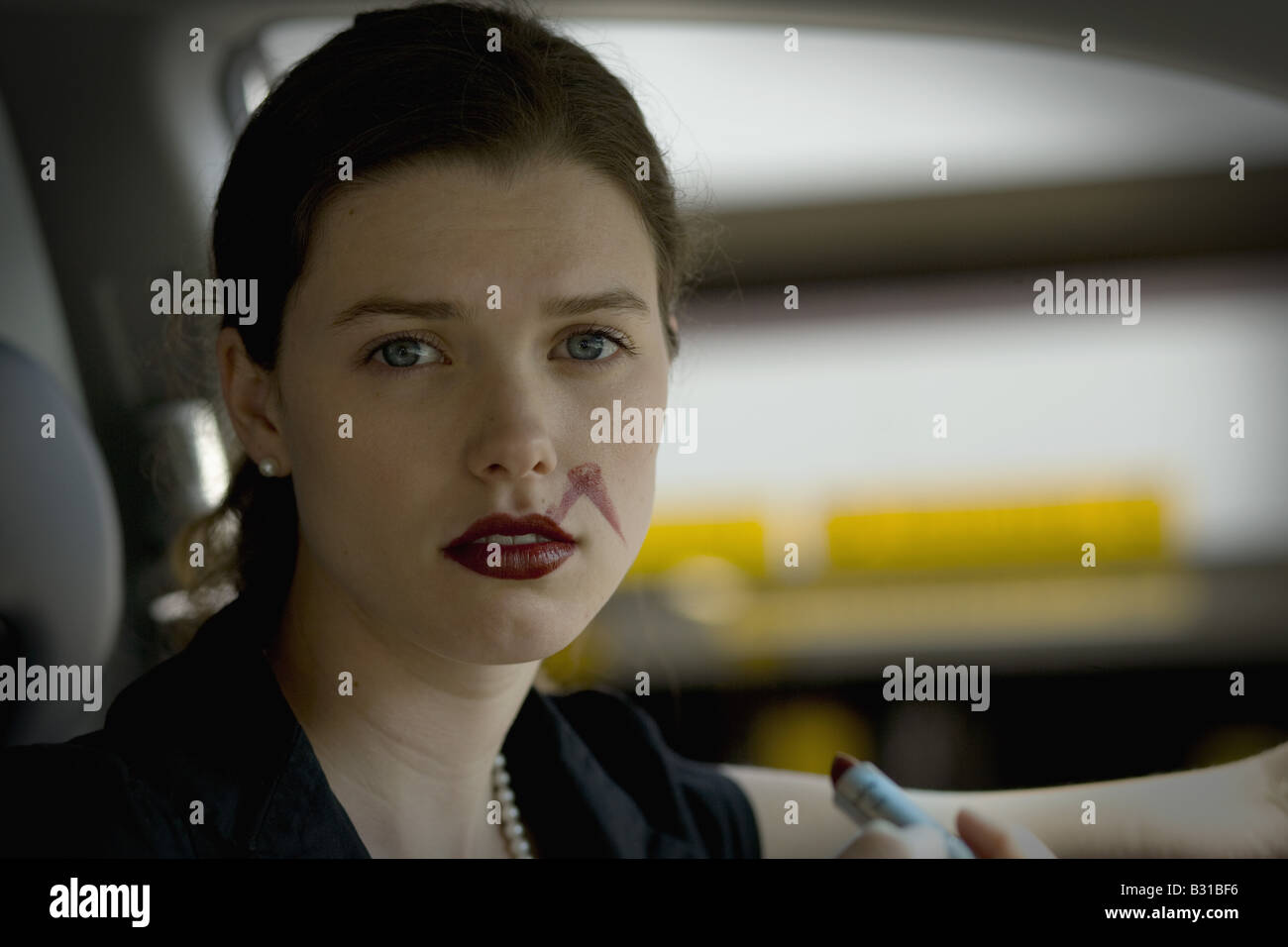 Giovane donna in auto con sbavature del rossetto Foto Stock