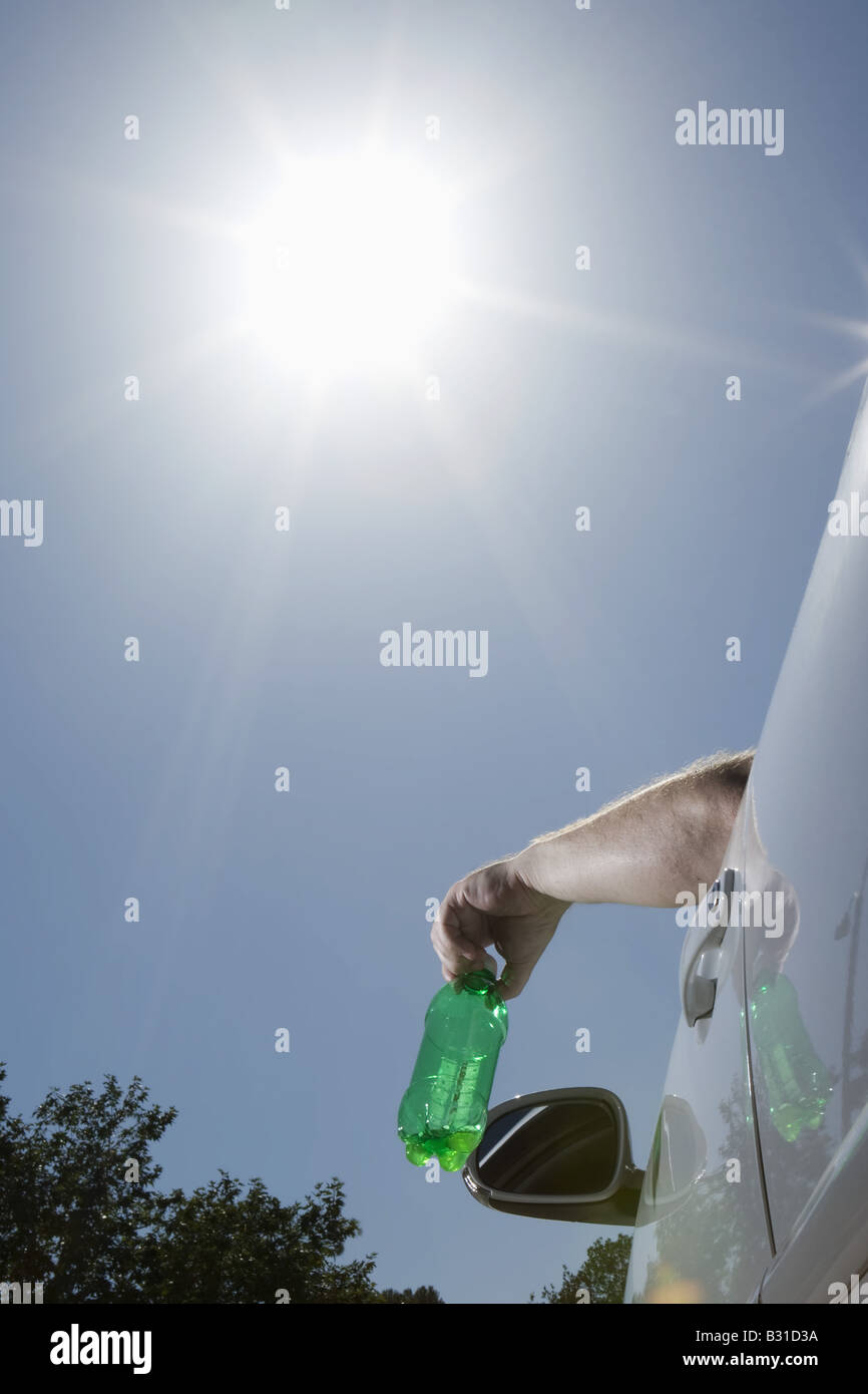 Uomo di gettare la bottiglia di plastica al di fuori della finestra di auto Foto Stock