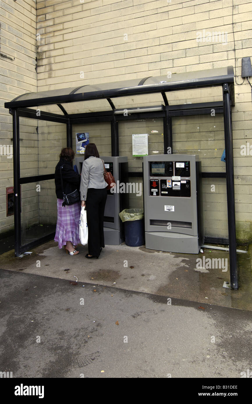 Due donne figura il ticket la macchina in un Parcheggio Foto Stock