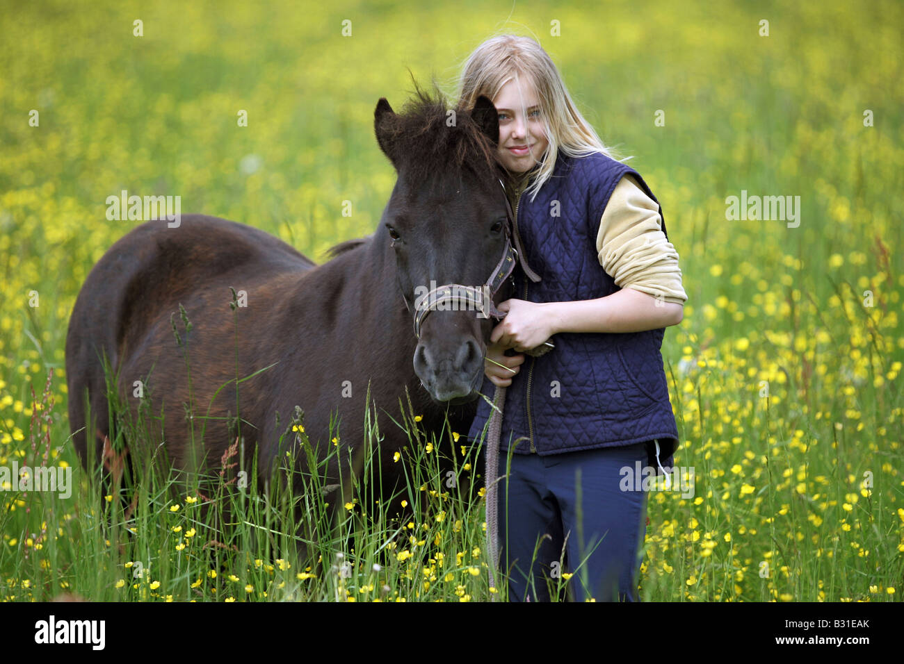 Ragazza giovane con un pony su un prato Foto Stock