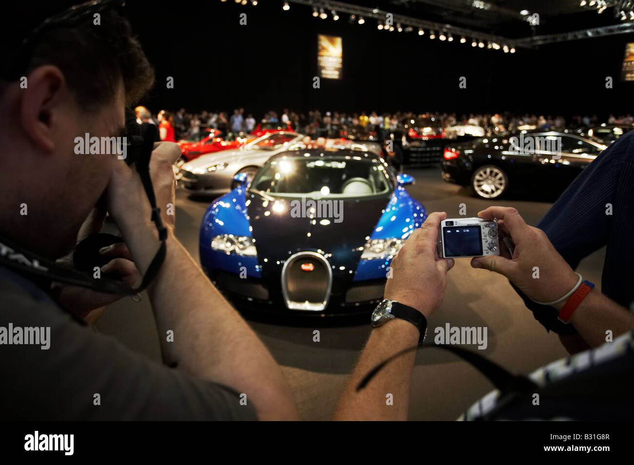 Gli scommettitori di visitatori e la Bugatti Veyron auto modello al British International Motor Show al centro Excel nei Docklands Londra Inghilterra Foto Stock