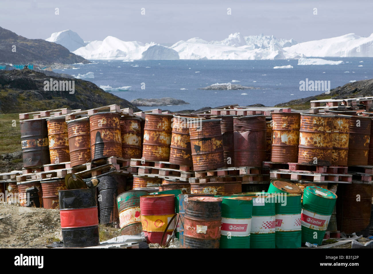 Rifiuti di barili di olio sulla tundra al di fuori di Illulissat in Groenlandia con gli iceberg dietro dal Illulissat fiordo di ghiaccio Foto Stock