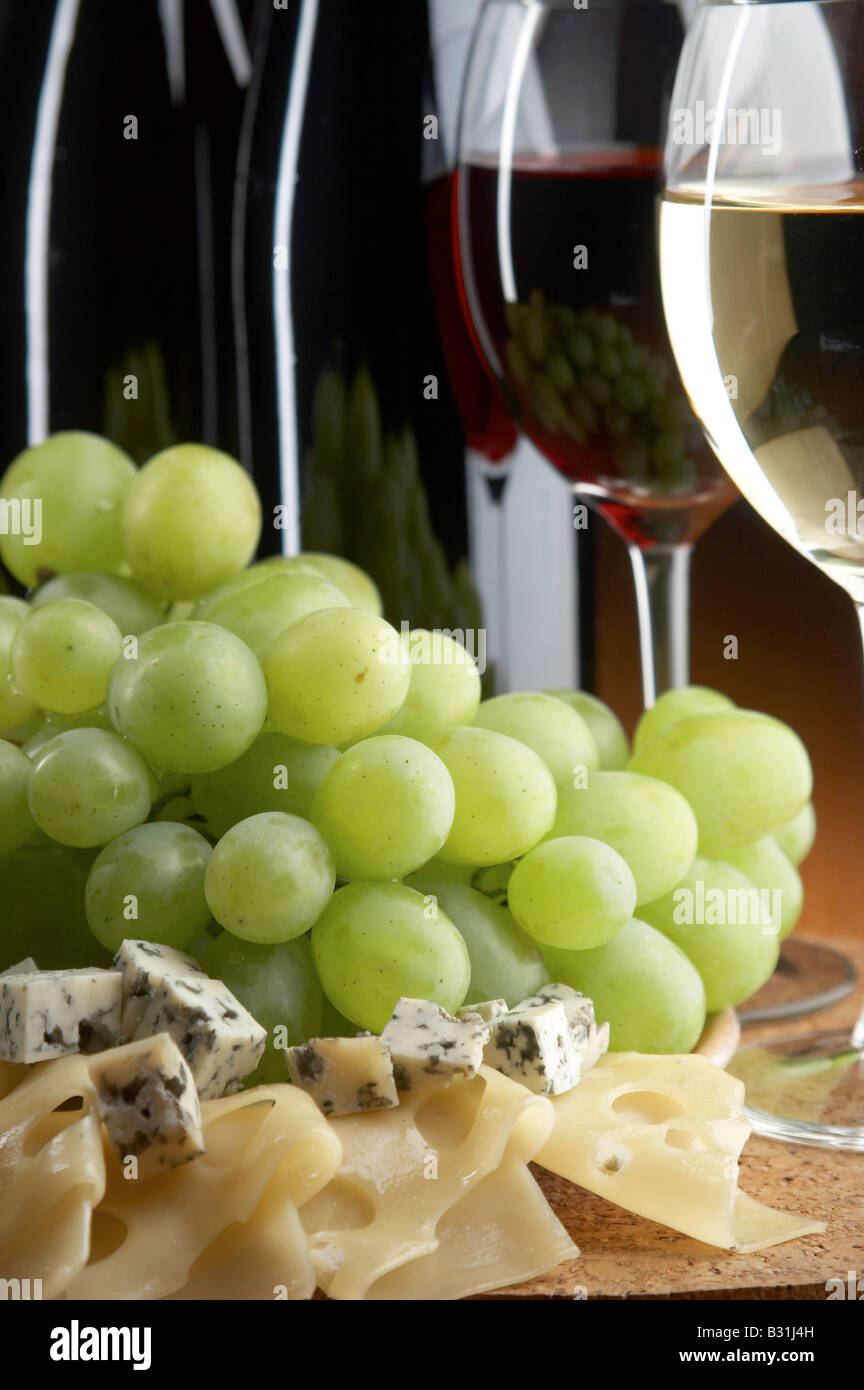 Natura morta con uva rossa di formaggi e vini bianchi su sfondo nero Foto Stock