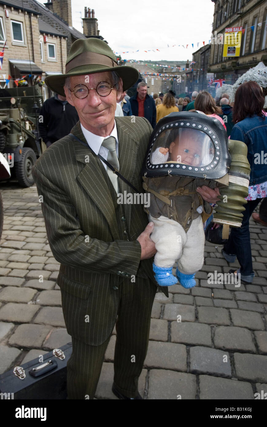 Uomo con una bambola in un bambino tutto gas mask Haworth 1940 s weekend 2008 Foto Stock