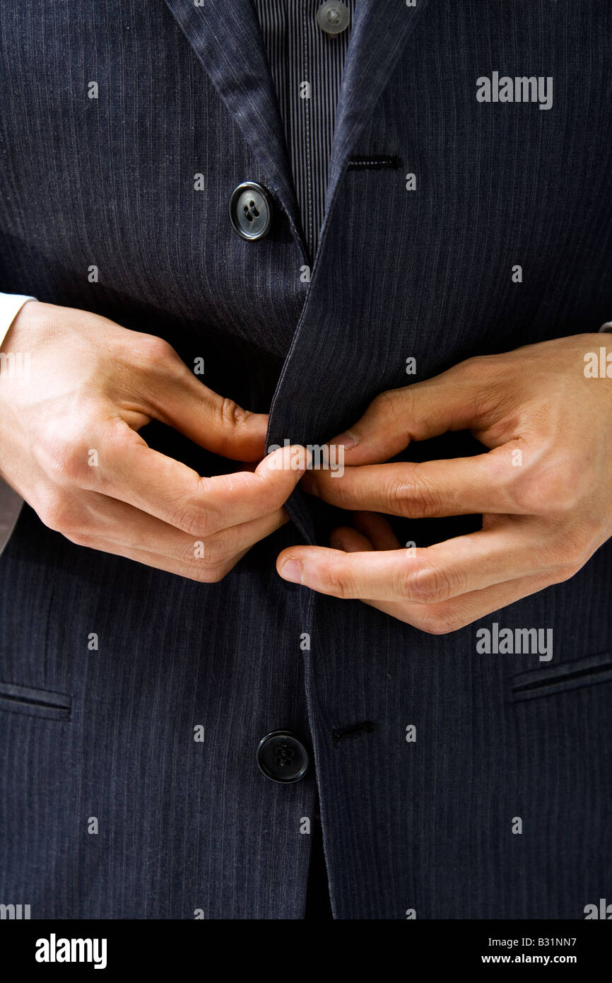 Mani unbuttoning un grigio pinstriped business suit closeup Foto Stock