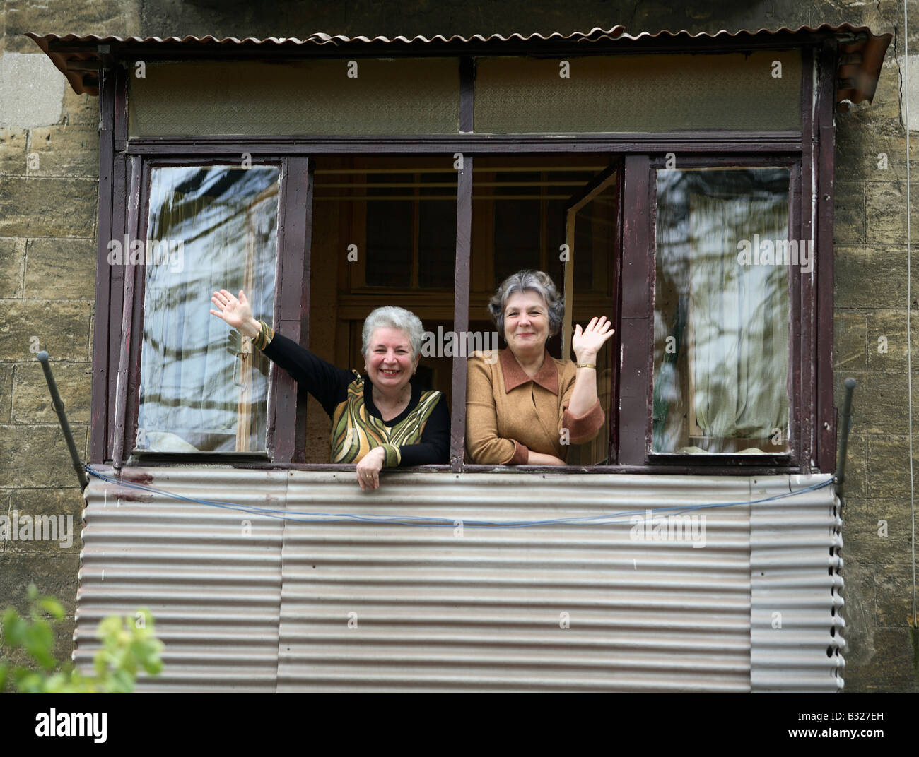 Due donne in piedi in una finestra e agitando, Odessa, Ucraina Foto Stock