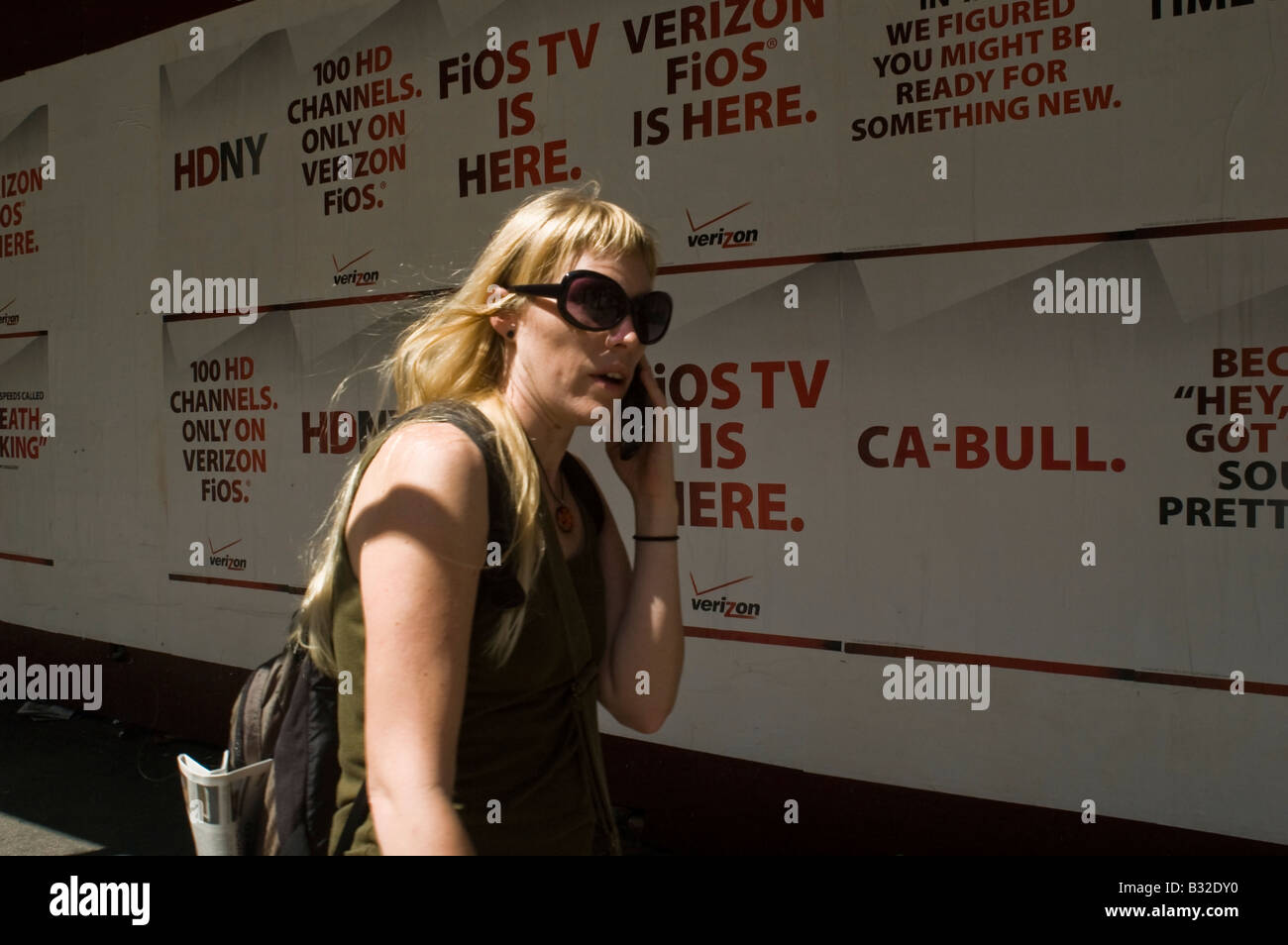 Una donna cammina passato poster pubblicità Verizon FiOS service in New York Foto Stock
