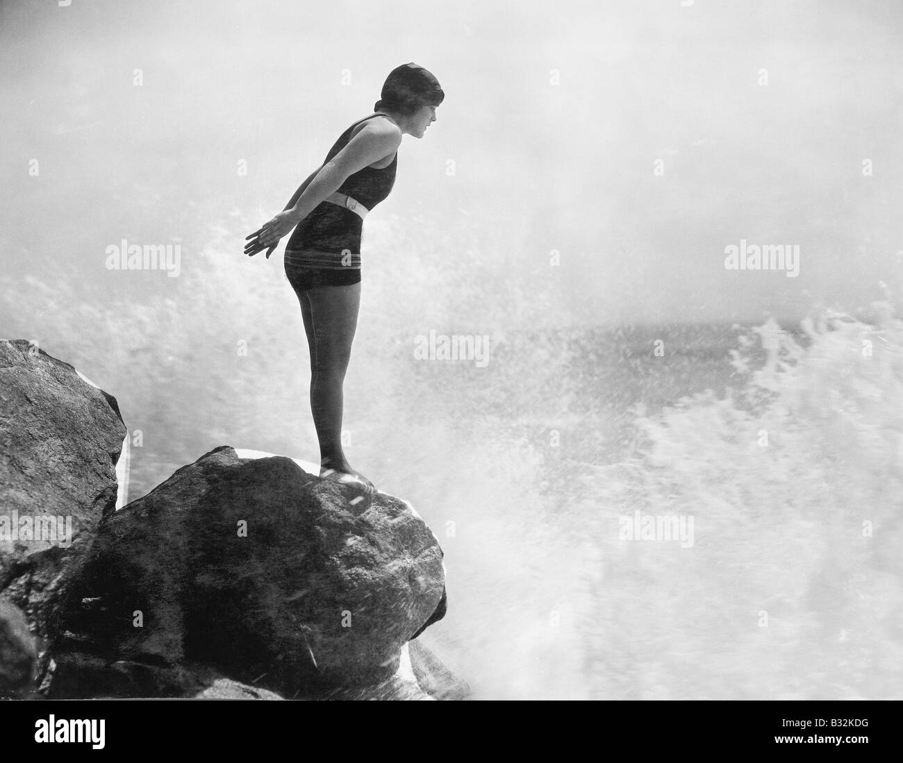 Nuotatore femmina sulla roccia sopra crashing surf Foto Stock Nuotatore femmina sulla roccia sopra crashing surf Foto Stock