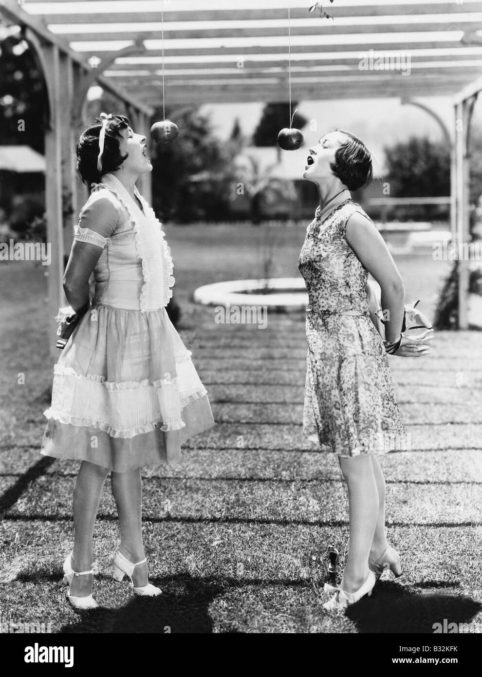 Le donne di mordere mele su stringhe di Halloween Foto Stock