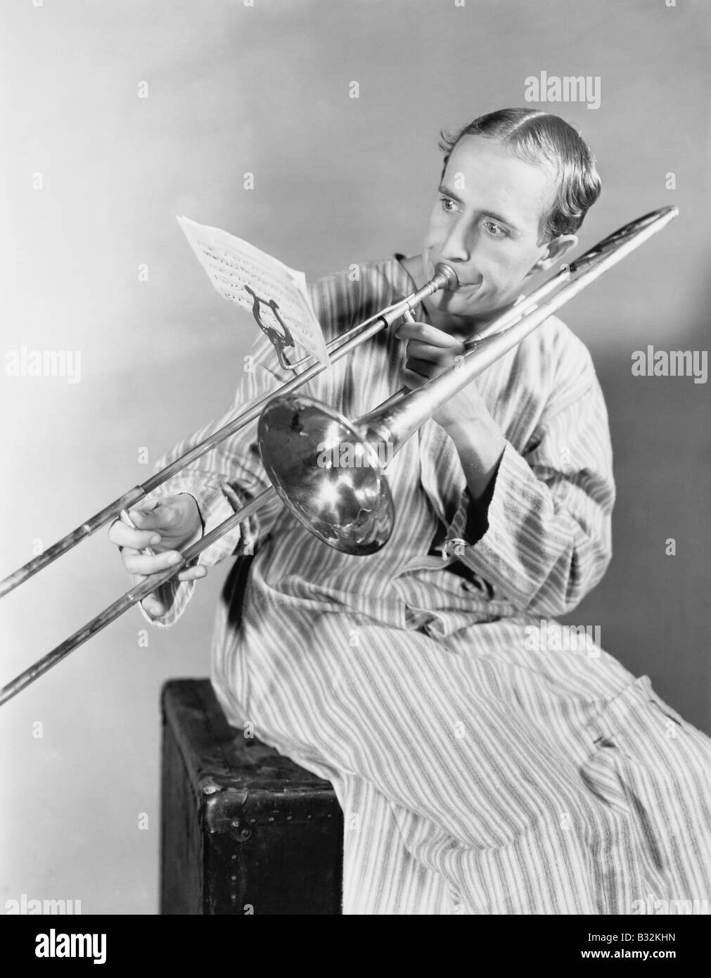 L'uomo gioca trombone in nightgown Foto Stock