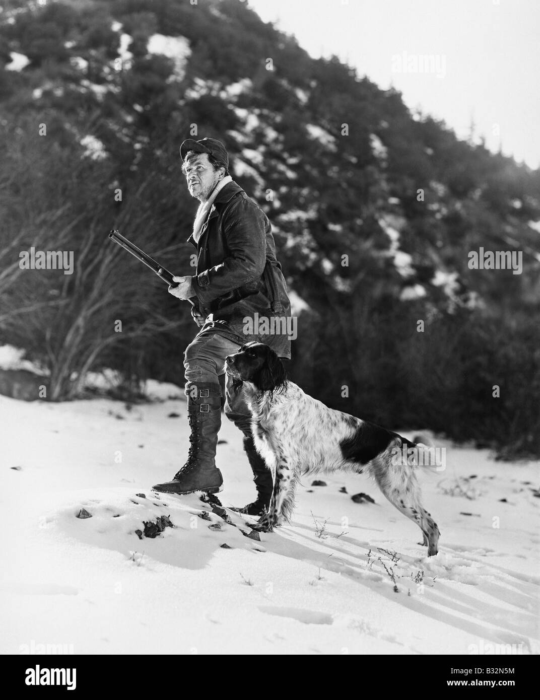 L'uomo caccia in montagne innevate con il cane Foto Stock