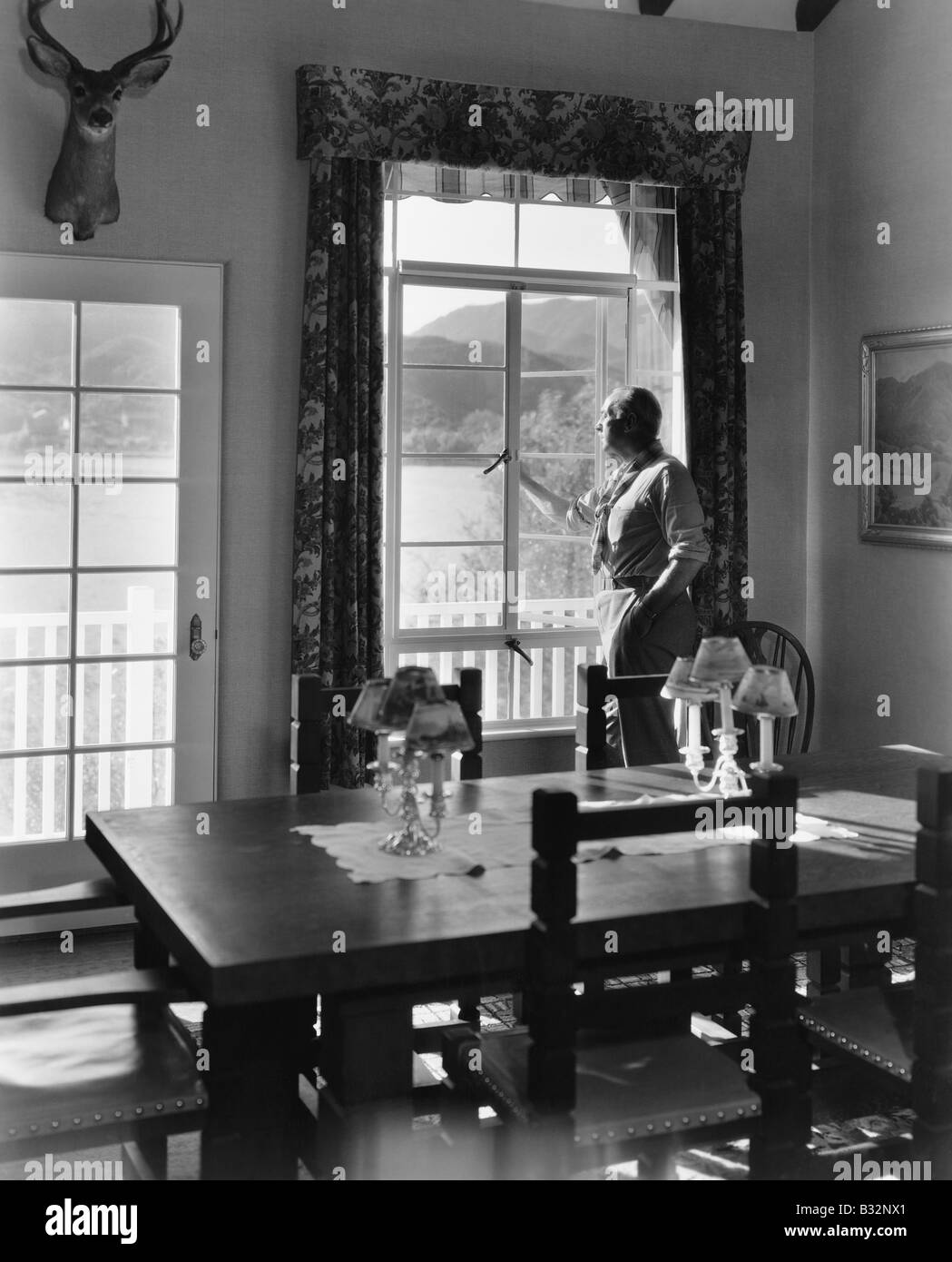 Uomo in piedi alla finestra in sala da pranzo Foto Stock