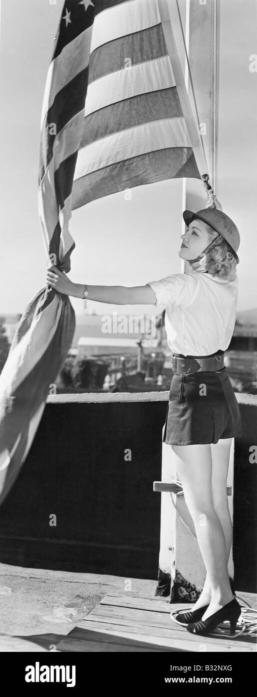 La donna alzando bandiera americana Foto Stock