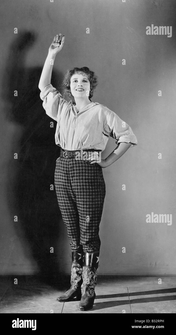 Giovane donna in piedi con la mano alzata e sorridente Foto Stock