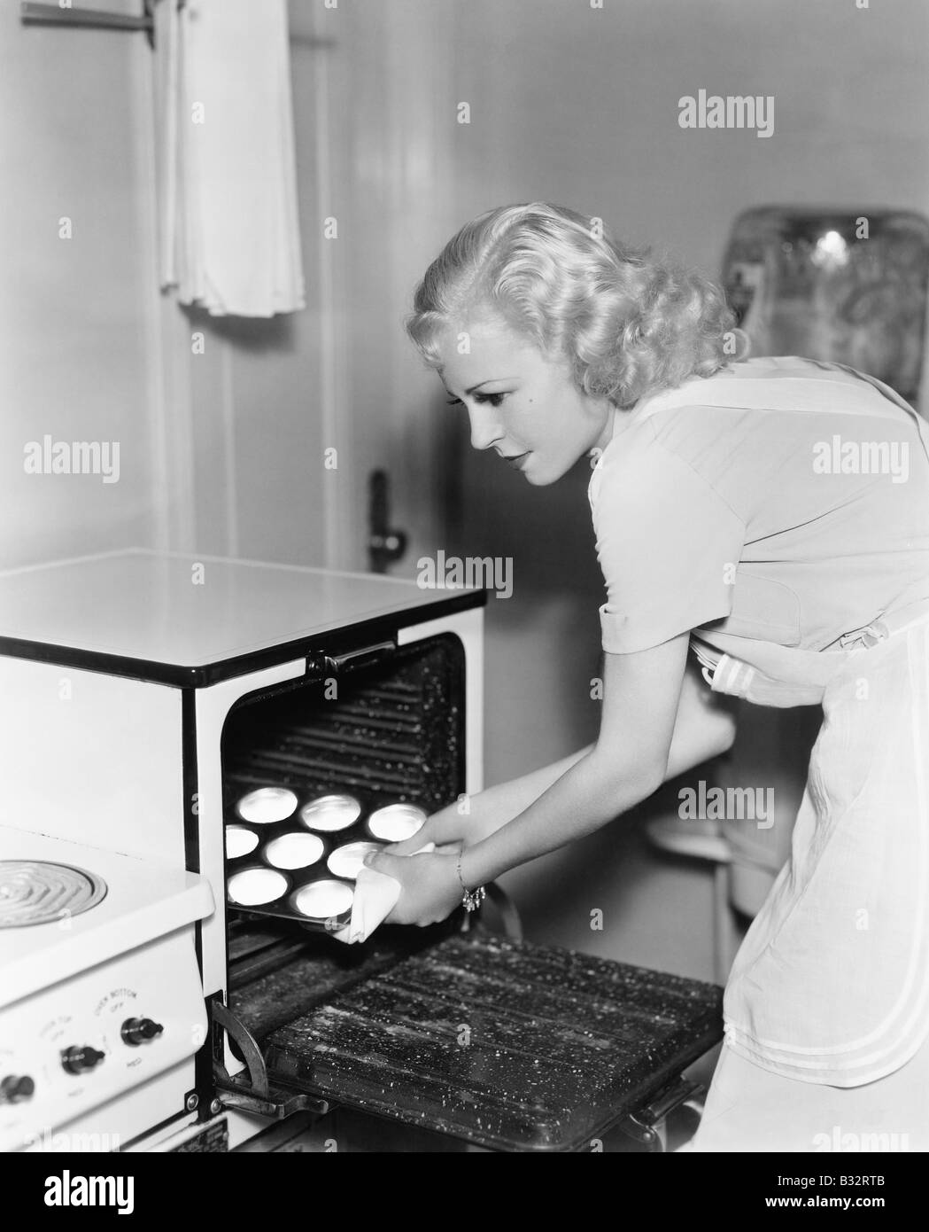 Giovane donna prendendo i cookie di un forno Foto Stock