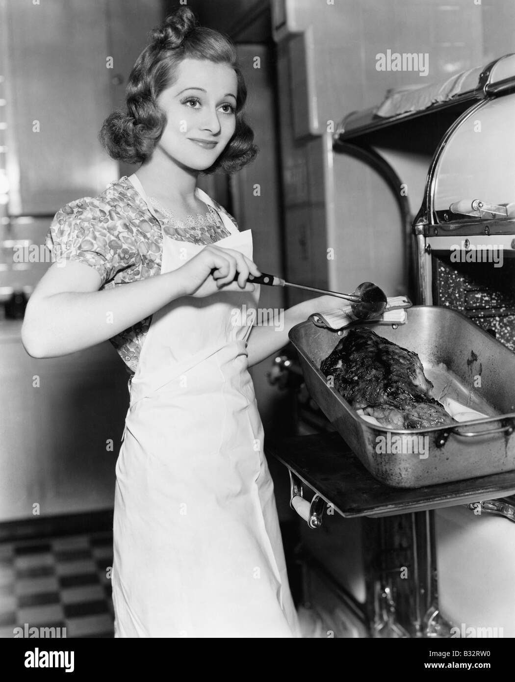 Giovane donna inumidendo un oca in cucina Foto Stock