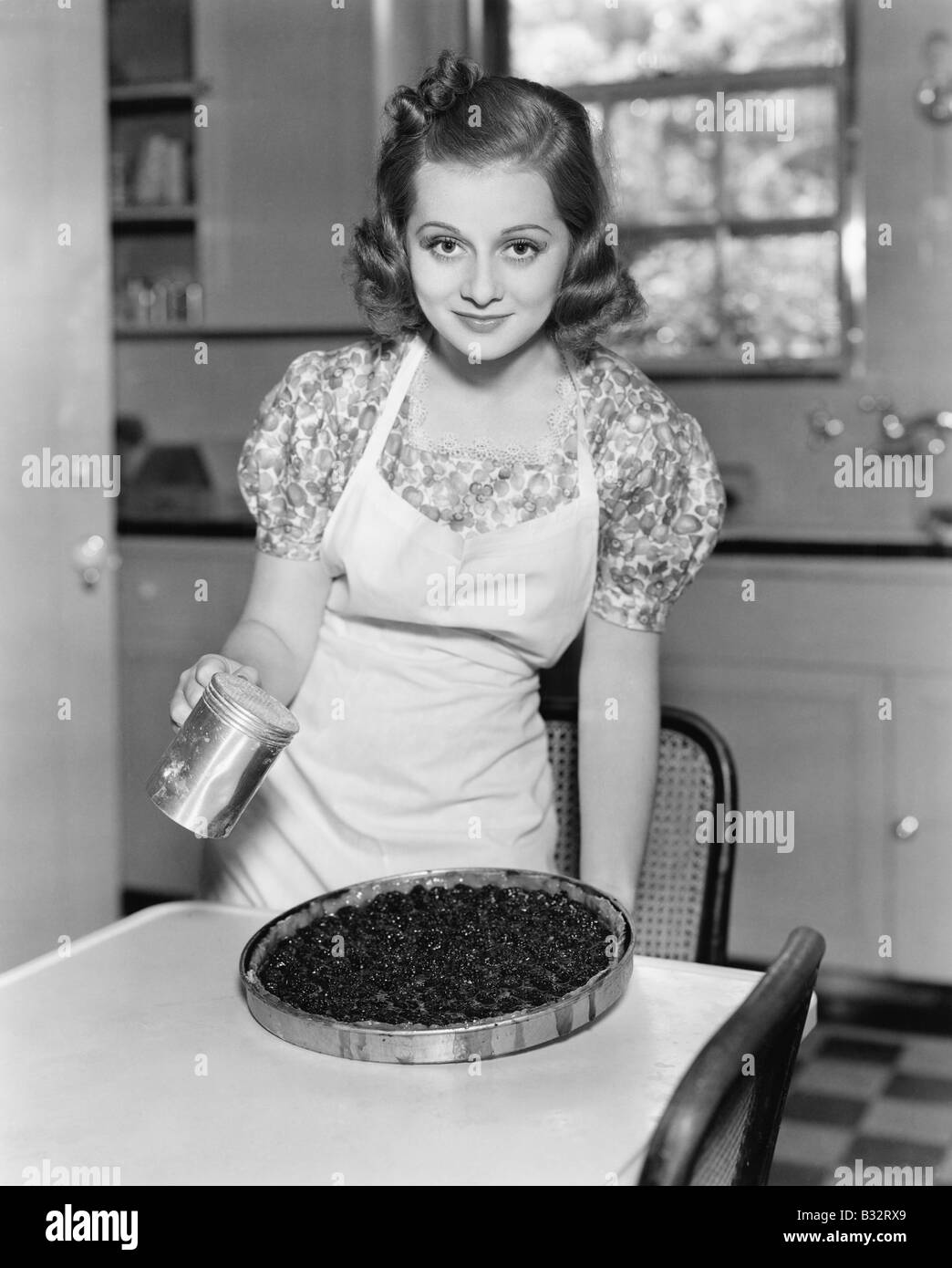 Ritratto di una giovane donna di preparare una torta ai mirtilli in cucina Foto Stock