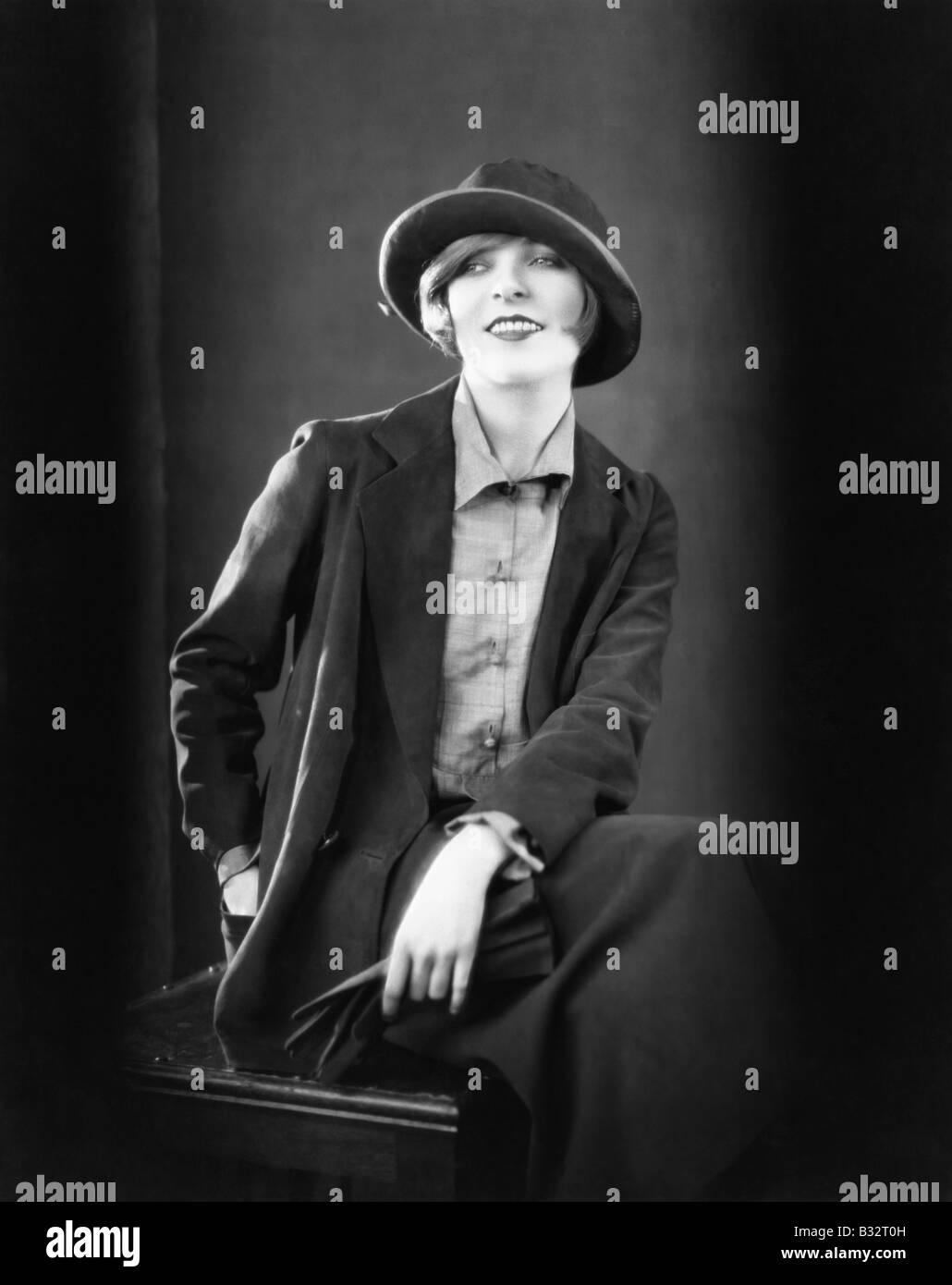 Ritratto di una donna seduta su uno sgabello e sorridente Foto Stock
